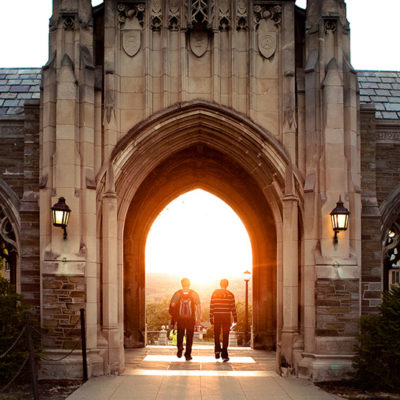 Students walk through the World War I Memorial archway at sunset.