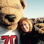 Cornell mascot bear Touchdown stands with their paw around a woman