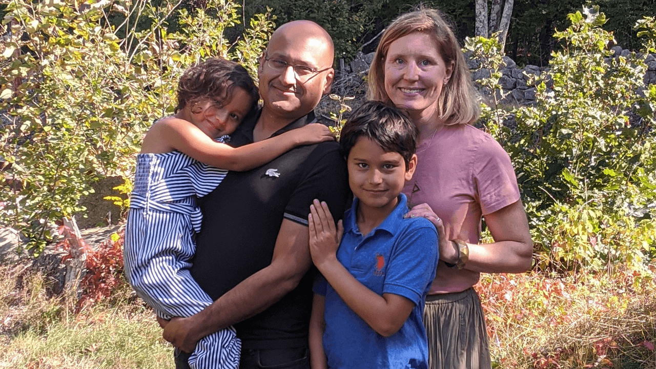 kashem holding his child and standing with his family for a photo