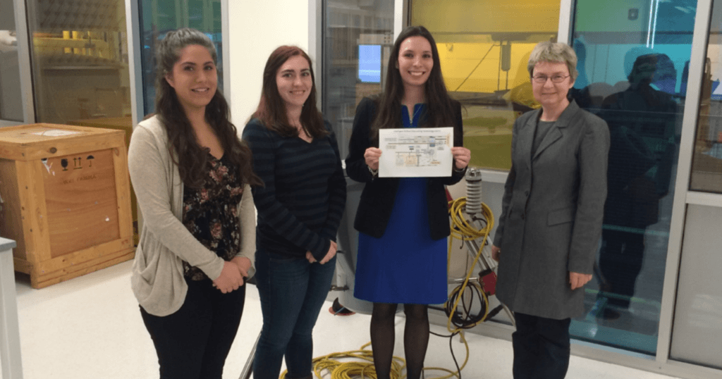 a group of students stand with a professor in her lab