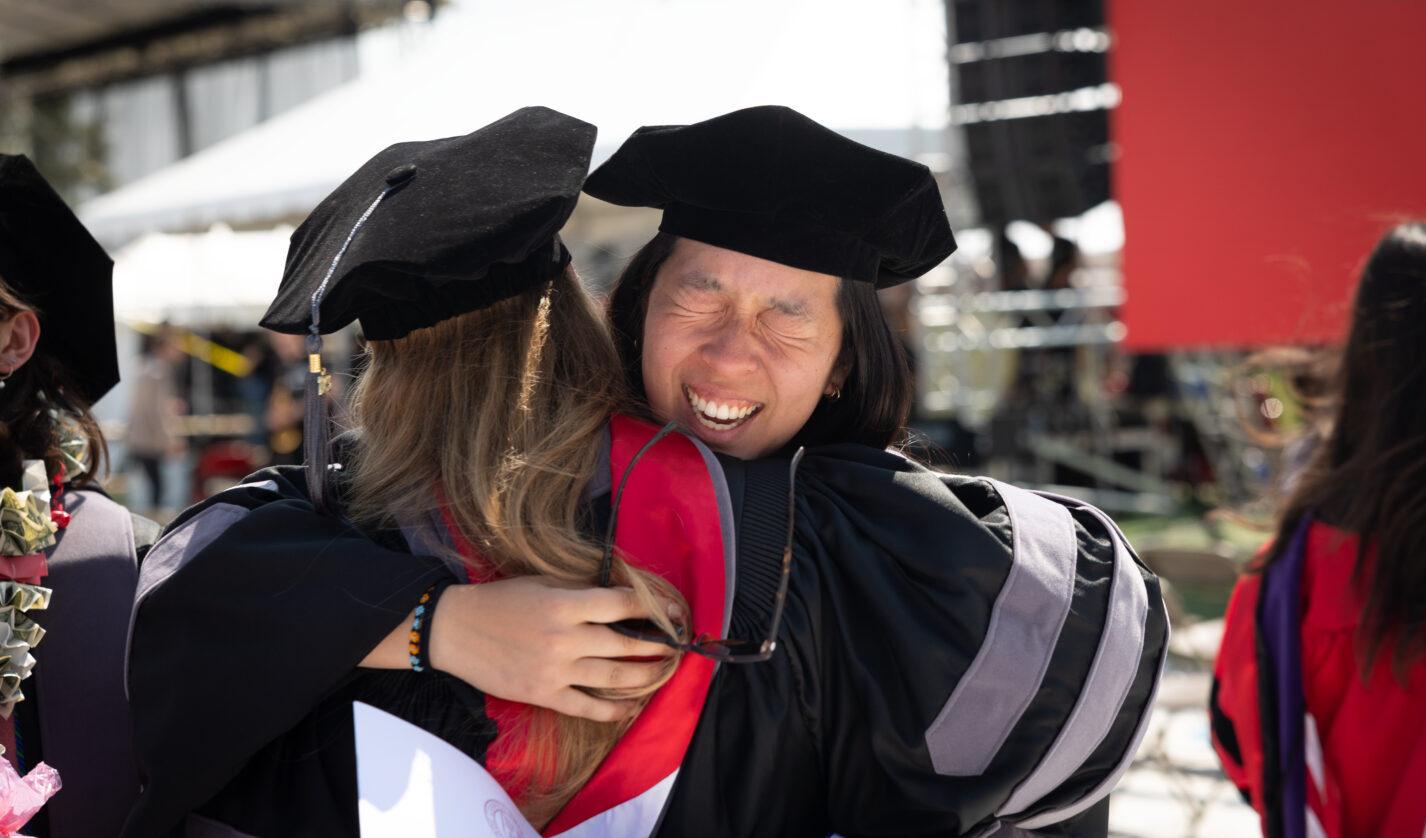 A student hugs a professor during commencement in 2023.