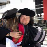 A student hugs a professor during commencement in 2023.