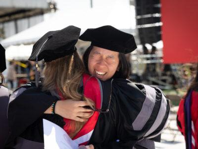 A student hugs a professor during commencement in 2023.