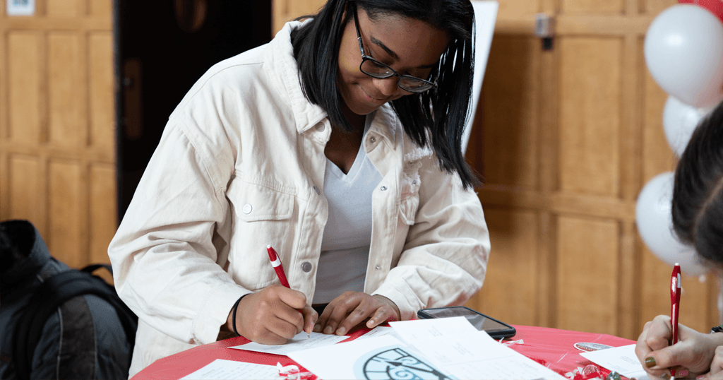 A student smiles while writing a thank-you postcard