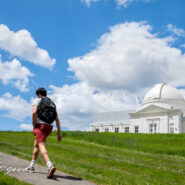 student walks by Fuertes Observatory in spring