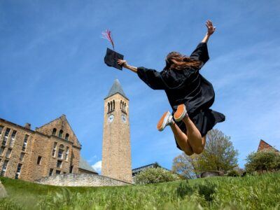 Student jumping near McGraw Tower for graduation.
