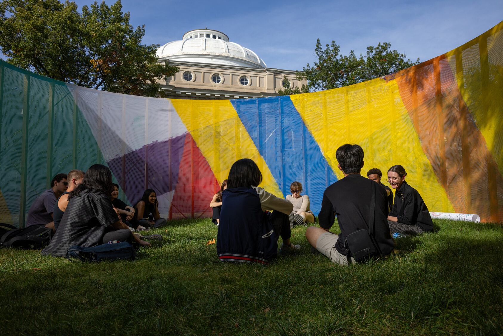 Assistant Professor Suzanne Lettieri hosts her B.Arch. Core Studio class in the Arts Quad on October 5, 2023. The fabric for the structure enveloping them was created during the Painting Public Spaces Workshop, led by Lettieri.