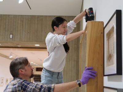 A Johnson Museum student intern and preparator work together on an installation in the galleries.