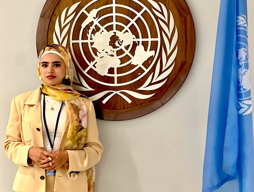 Mursal poses in front of the UN insignia and flag at the UN headquarters in NYC