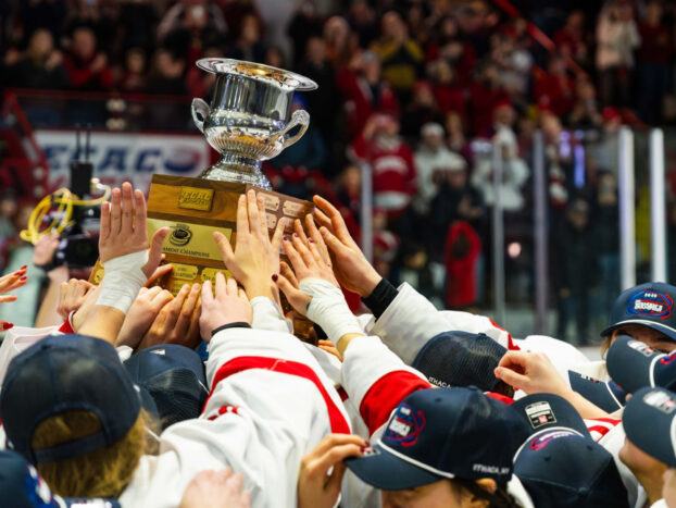 Women's ice hockey team holding up a trophy